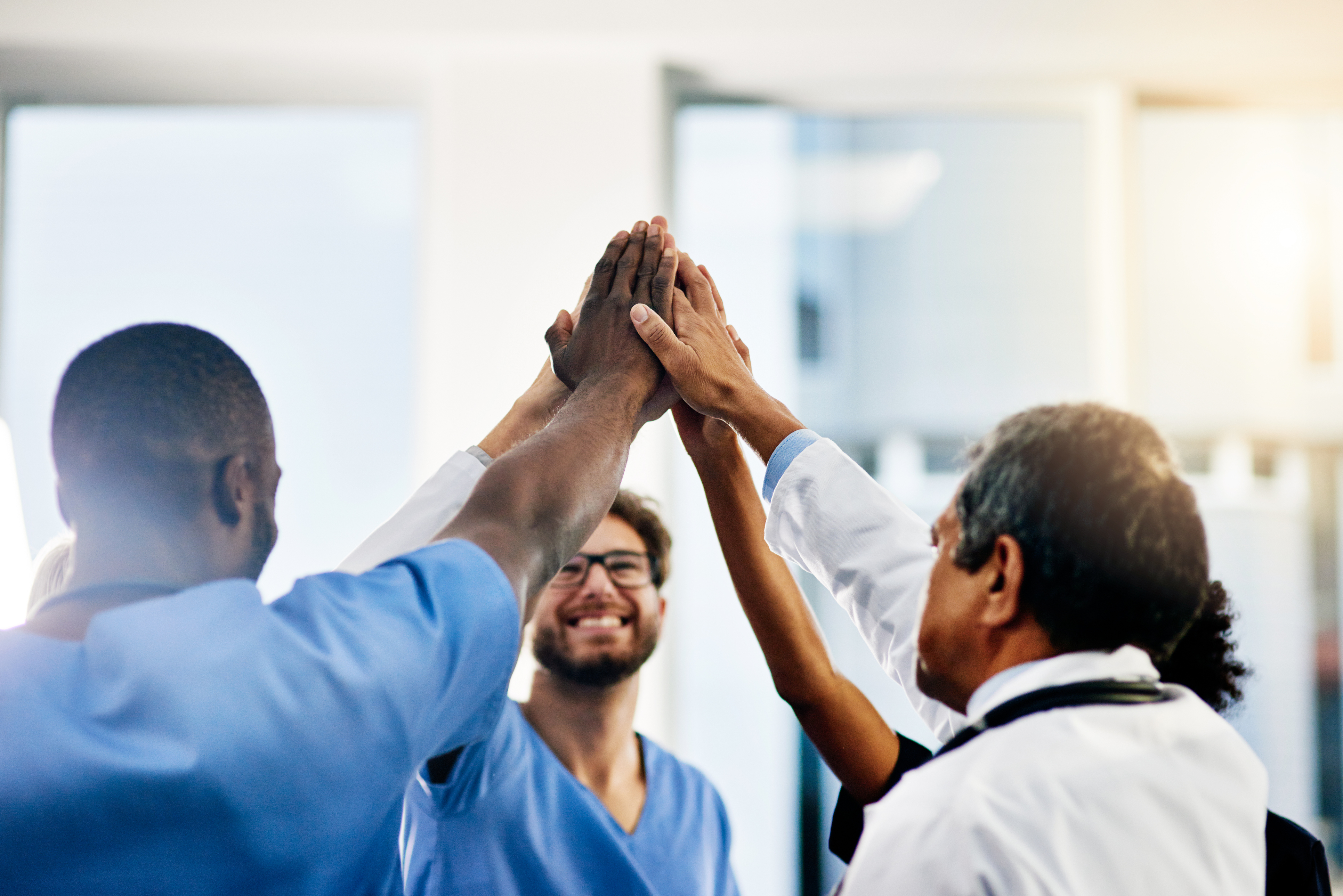 Shot of a diverse team of doctors giving each other a high five in a hospital